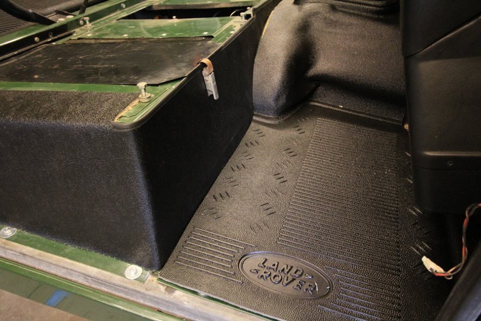 A new genuine Land Rover rubber floor mat and seat box Hardura trim is installed.